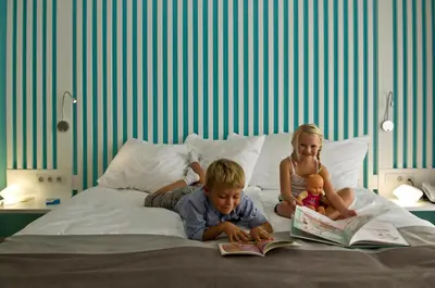a boy and a girl sitting on a bed reading books at Radisson Blu Resort & Spa, Ajaccio Bay in Porticcio