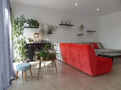 a living room with a red couch and a table with plants at Villa piscine vue mer in Pietrosella