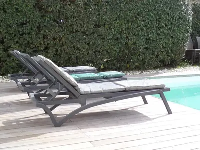 a bench with pillows sitting next to a pool at Villa piscine vue mer in Pietrosella