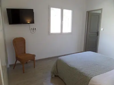 a bedroom with a bed and a chair and a television at Villa piscine vue mer in Pietrosella