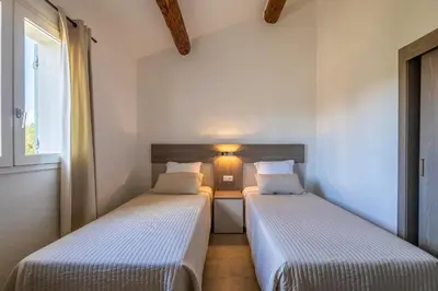 two beds in a small room with a window at Résidence Santa Monica in Bonifacio