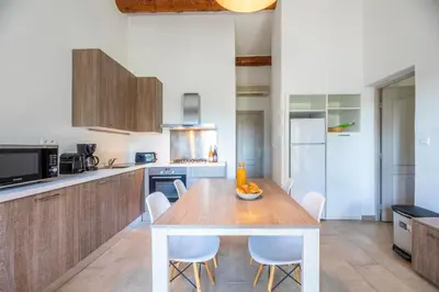 a kitchen with a wooden table and white chairs at Résidence Santa Monica in Bonifacio