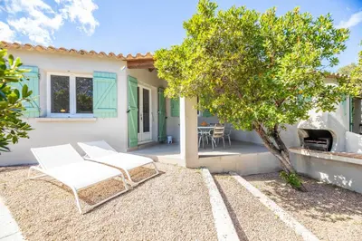 a patio with two chairs and a tree in front of a house at Résidence Santa Monica in Bonifacio