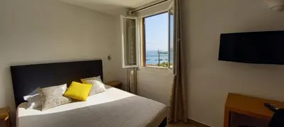 a bedroom with a bed with a window and a television at Hôtel du Golfe in Bonifacio