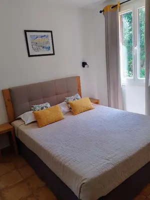 a bedroom with a bed with yellow pillows on it at Hôtel du Golfe in Bonifacio