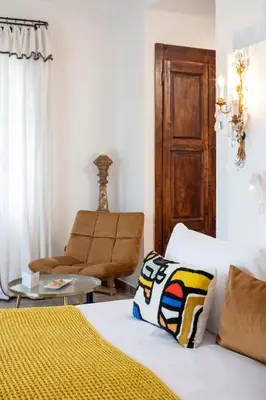 a bedroom with a bed and a chair at Hôtel La Dimora & Spa in Saint-Florent