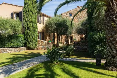 a house with a palm tree and a garden at Hôtel La Dimora & Spa in Saint-Florent