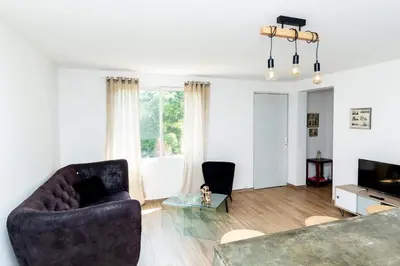 a living room with a couch and two chairs and a television at Dans mon jardin in Ajaccio