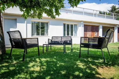 three chairs and a table in front of a house at Dans mon jardin in Ajaccio