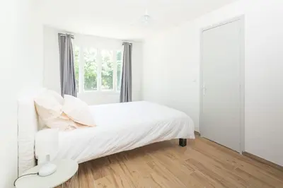 a white bedroom with a bed and a window at Dans mon jardin in Ajaccio