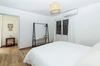 a white bedroom with a bed and a window at Dans mon jardin in Ajaccio