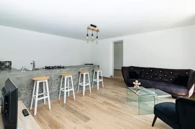 a living room with a couch and a bar with stools at Dans mon jardin in Ajaccio