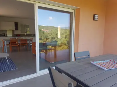 a dining room with a table and a sliding glass door at Sarl Valinco Locations in Olmeto