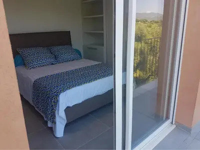 a bedroom with a bed with a view of a balcony at Sarl Valinco Locations in Olmeto