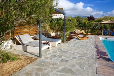a patio with two lounge chairs next to a swimming pool at Résidence U Rapalinu in Molini