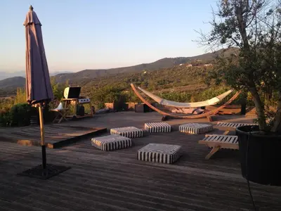 a patio with a hammock and chairs and an umbrella at Casa Vadde Lungha superbe vue mer 8 personnes in Coti-Chiavari
