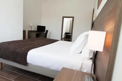 a bedroom with a bed and a desk with a lamp at Hôtel Des Nacres in Ventiseri