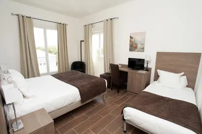 a hotel room with two beds and a desk with a computer at Hôtel Des Nacres in Ventiseri