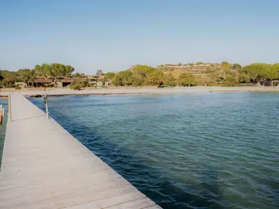 a wooden pathway over the water with a beach at Apartment Cala Sultana-3 by Interhome in Usciolo