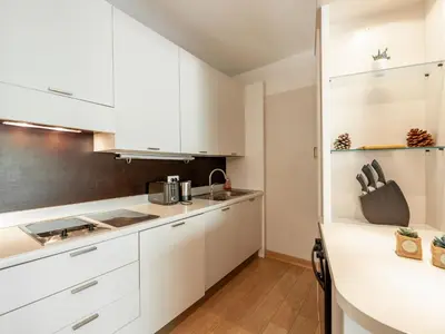 a kitchen with white cabinets and wooden floors at Apartment Cala Sultana-3 by Interhome in Usciolo