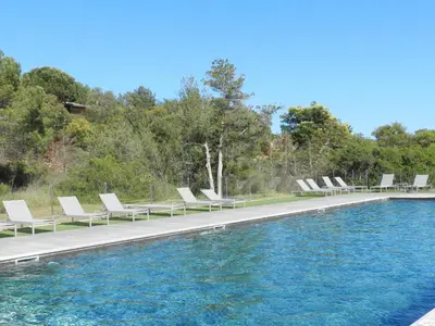 a row of lounge chairs next to a swimming pool at Apartment Cala Sultana-7 by Interhome in Usciolo