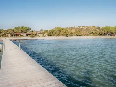 a wooden pathway over the water with a beach at Apartment Cala Sultana-7 by Interhome in Usciolo