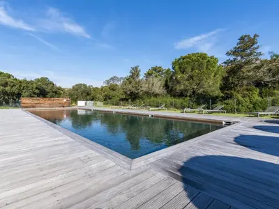 a large swimming pool with a wooden deck at Apartment Cala Sultana-7 by Interhome in Usciolo