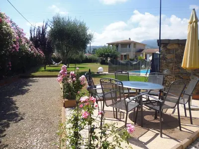 a patio with a table and chairs and flowers at Villa mit grosser Sommerküche und Pool, 8 Minuten zum Sandstrand Cap Sud in LʼArena