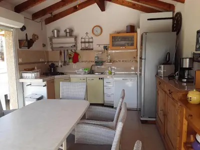 a kitchen with a table and a refrigerator at Villa mit grosser Sommerküche und Pool, 8 Minuten zum Sandstrand Cap Sud in LʼArena