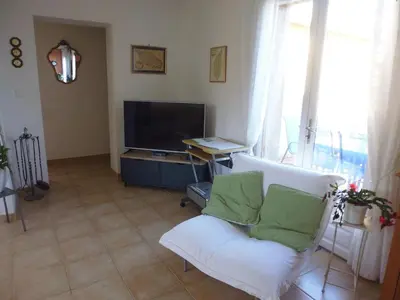 a living room with a white chair and a television at Villa mit grosser Sommerküche und Pool, 8 Minuten zum Sandstrand Cap Sud in LʼArena