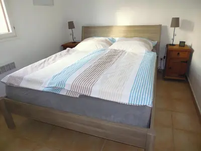 a large bed in a bedroom with a wooden headboard at Villa mit grosser Sommerküche und Pool, 8 Minuten zum Sandstrand Cap Sud in LʼArena