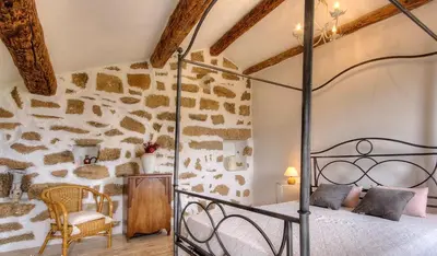 a bedroom with a bed and a stone wall at Gîte à Piscia de Figari Petru Barbara in Figari