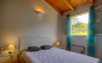 a bedroom with a bed with two pillows and a window at Gîte à Piscia de Figari Petru Barbara in Figari