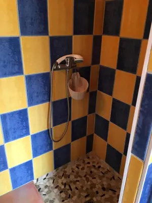 a shower in a bathroom with blue and yellow tiles at Caseddu di Chjarastella in Figari