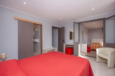 a bedroom with a red bed and a chair at Hotel Arcu Di Sole in Propriano