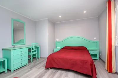 a bedroom with a green bed and a desk at Hotel Arcu Di Sole in Propriano