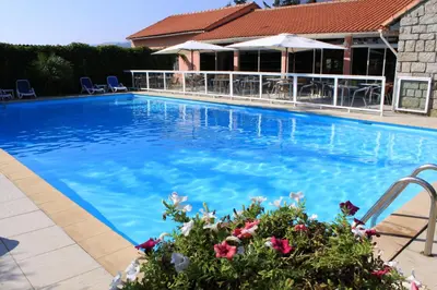 a large blue swimming pool with chairs and flowers at Hotel Arcu Di Sole in Propriano