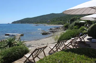a group of chairs sitting on a beach next to the water at Les Bungalows de Figha in Tarcu