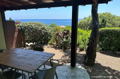 a table and chairs on a patio with a view of the ocean at Les Bungalows de Figha in Tarcu