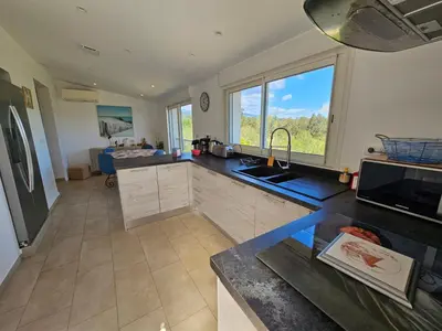 a kitchen with a sink and a large window at Emma in Sari Solenzara