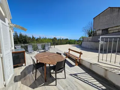 a patio with a wooden table and chairs and a bench at Emma in Sari Solenzara