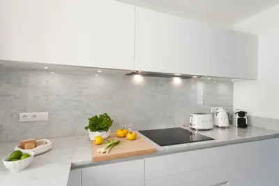 a white kitchen with a sink and fruits and vegetables at Superbe T3 sur la Marina de Bonifacio in Bonifacio