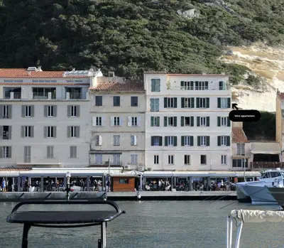 a boat in the water next to some buildings at Superbe T3 sur la Marina de Bonifacio in Bonifacio