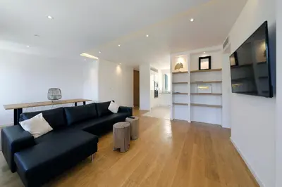 a living room with a black couch and a television at Superbe T3 sur la Marina de Bonifacio in Bonifacio