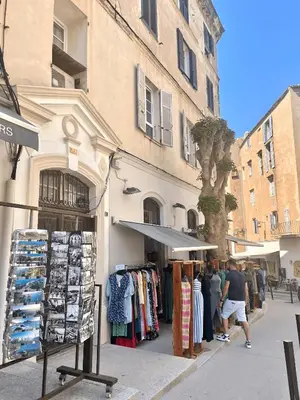 a store on the side of a street with people standing outside at L'Escale chambres privées chez l'habitant JFDL in Bonifacio