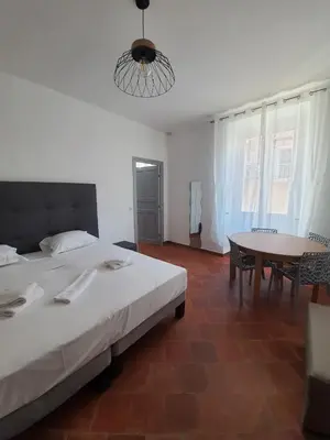 a bedroom with a desk and a television on the wall at L'Escale chambres privées chez l'habitant JFDL in Bonifacio