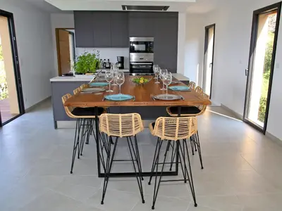 a kitchen with a large wooden table with wine glasses on it at Villa Vue Mer, piscine chauffée, tennis in Porticcio