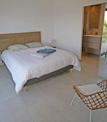a bedroom with a large bed and a chair at Villa Vue Mer, piscine chauffée, tennis in Porticcio