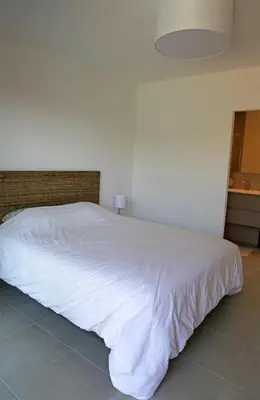 a large white bed in a bedroom with a lamp at Villa Vue Mer, piscine chauffée, tennis in Porticcio