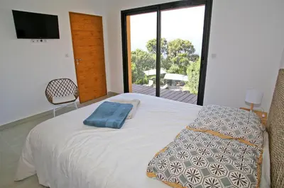 a bedroom with a bed and a large window at Villa Vue Mer, piscine chauffée, tennis in Porticcio